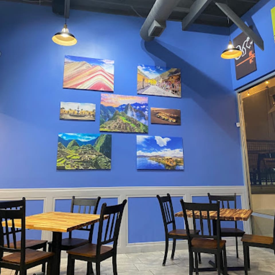 Cuzco's Peruvian Restaurant interior with blue walls, Peruvian landscape art, and wooden tables and chairs.