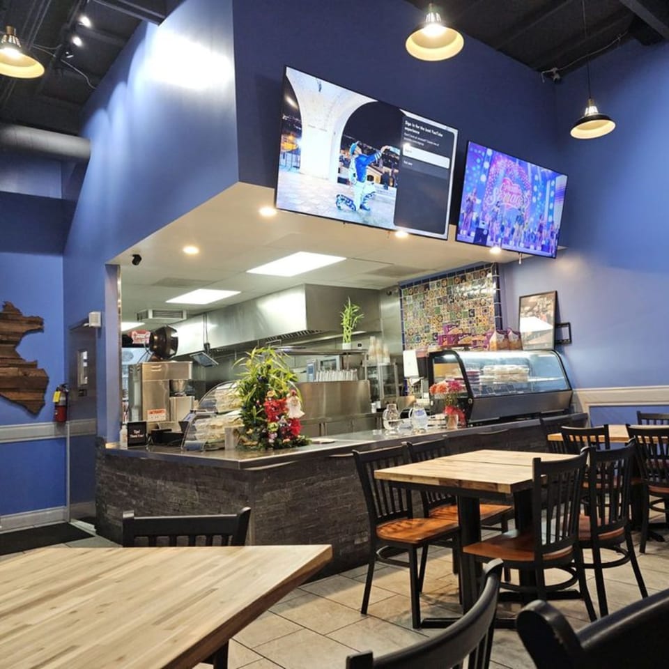 Interior of Cuzco's Peruvian Restaurant with blue walls, a service counter, and dining tables.