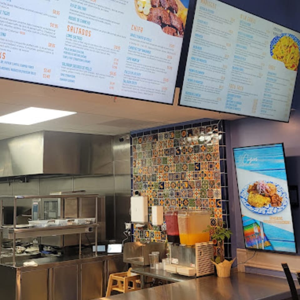 Cuzco's Peruvian Restaurant interior with menu boards, kitchen area, and drink dispensers.
